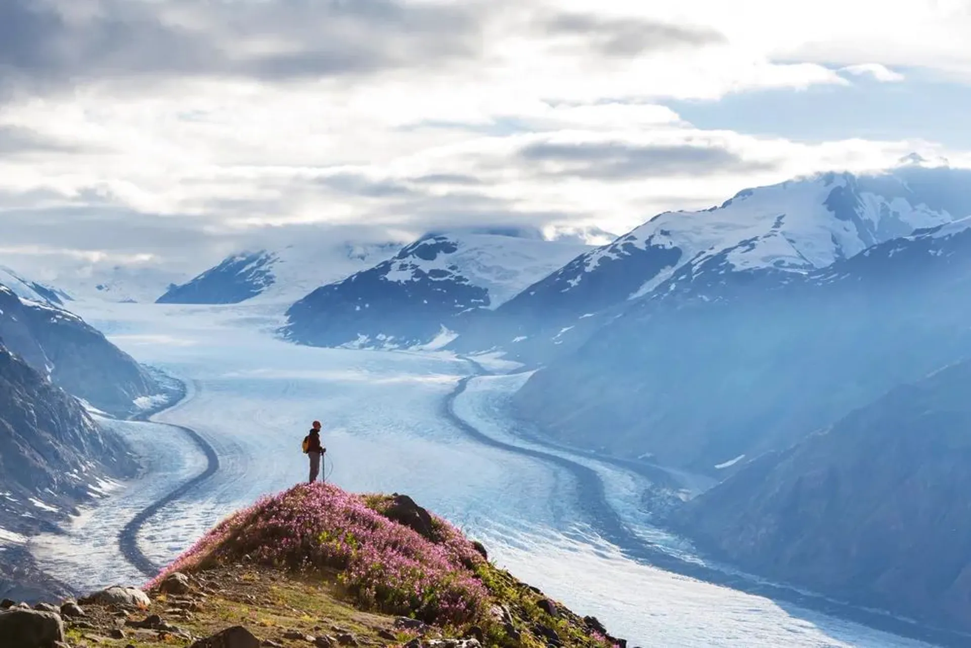 Person standing on ridge overlooking Alaskan glacier and mountains